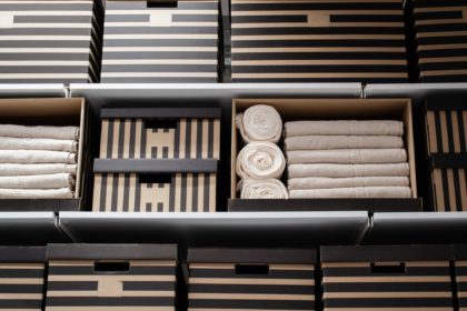 Cardboard striped boxes and white towels on hanging shelves. The concept of home storage