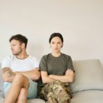 Conflicting couple sitting on sofa in closed poses