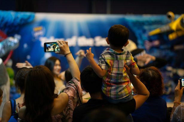 Father hold his son on his shoulder to see the show in Sea Life Bangkok Ocean World, Thailand