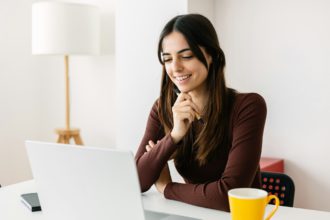 Portrait of young adult student sitting on table using laptop learning online